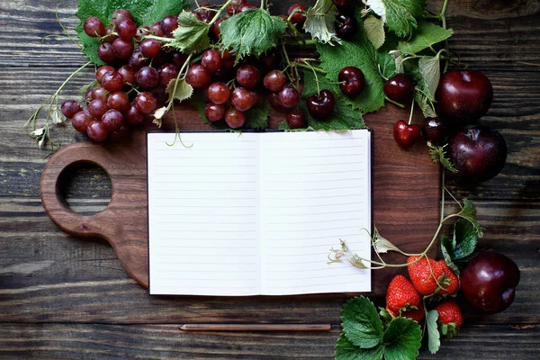 Frutas domésticas orgânicas vermelhas e placa de corte com livro de receitas — Fotografia de Stock