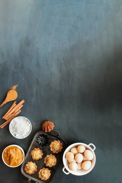 Pompoen muffins en ingrediënten over donkere achtergrond — Stockfoto