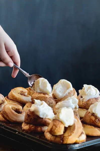 Hand Topping Gourmet Cinnamon Buns with Icing — стокове фото