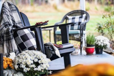 Adirondack sallanan sandalyede geleneksel bufalo stili battaniye ve veranda üzerindeki yastıkları aile yadigarları, beyaz ve turuncu anneler ile sonbahar süslemiştir. Arka planda bulanık bahçe ile seçmeli odak.