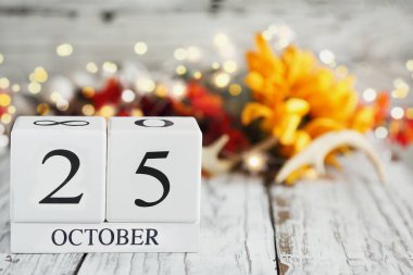 Tahta bir masanın üzerinde 25 Ekim ve sonbahar süslemeleri olan beyaz tahta takvim blokları. Bulanık arkaplan ile seçmeli odak. 