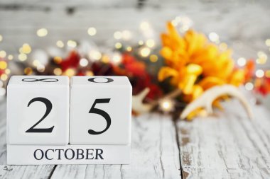 Tahta bir masanın üzerinde 25 Ekim ve sonbahar süslemeleri olan beyaz tahta takvim blokları. Bulanık arkaplan ile seçmeli odak. 