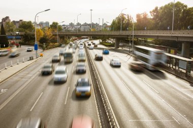 Arabalar hareket bulanıklığı içinde yol boyunca vızıldayarak.