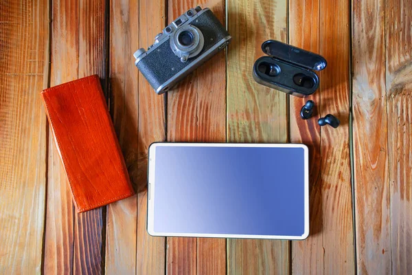 Старые планшеты камеры и беспроводные наушники на деревянном рабочем столе — стоковое фото