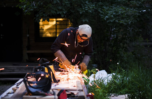 Человек сварки за пределами дома в летний день
