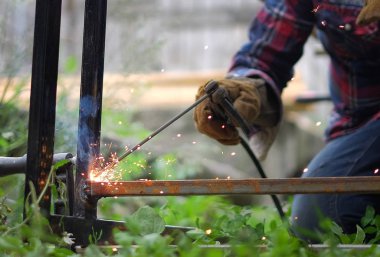 Bir yaz gününde dışında metal konstrüksiyon kaynak koruyucu maskeli adam.