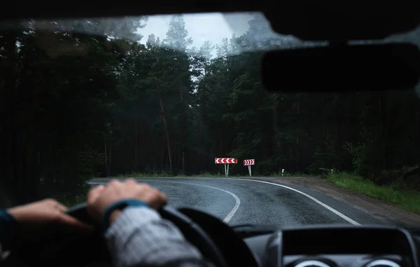 Stuurprogramma's hand op een stuurwiel in een auto op een weg — Stockfoto