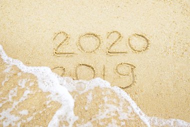 Yeni Yılınız Kutlu Olsun. 2020 ve 2019 nerede 2019 dalga tarafından yıkanıyor kum üzerinde yazılmış
