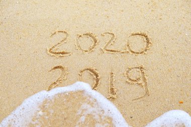 Yeni Yılınız Kutlu Olsun. 2020 ve 2019 nerede 2019 dalga tarafından yıkanıyor kum üzerinde yazılmış