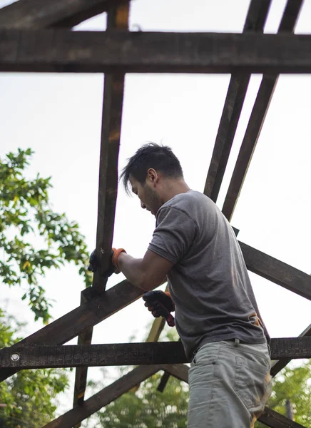 Hombre construyendo techo de madera trabajando con martillo — Foto de Stock