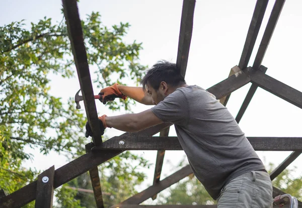 Hombre construyendo techo de madera trabajando con martillo — Foto de Stock