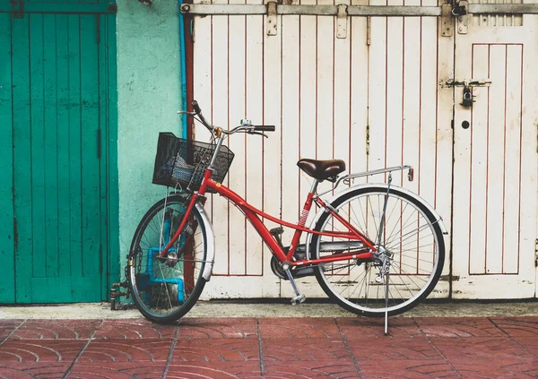 Red bicycle parked in front of white and green wall — Stock Photo, Image