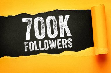 Yırtık bir kağıt arkaplanda gösterilen 700K FOLLOWERS metni sıkıntılı yazılar, sosyal medya büyümesini sembolize ediyor, kilometre taşı başarısı, çevrimiçi topluluk ve dijital başarı kutlamalarını simgeliyor
