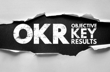 Yırtılan kağıdın altında OKR Hedef Anahtar Sonuçları vurgulandı. İş yönetimi aracı, kurumsal planlama, performans takibi ve organizasyonel başarı stratejisi