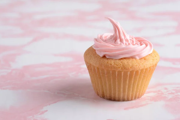 大理石桌上粉红霜的纸杯蛋糕 — 图库照片