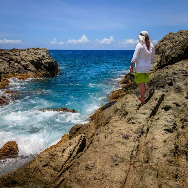 Cliff üzerinde duran ve izlerken kadın Adası üzerinde sörf 