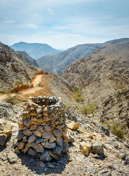 フォア グラウンドで岩石ピラミッドとアラブ首長国連邦フジャイラ Hajar 山脈の未舗装の道路 — ストック写真