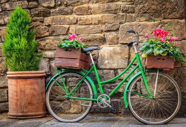 イタリア フィレンツェの石壁の横に花のあるボックスと緑の自転車 — ストック写真
