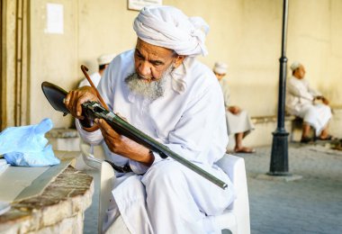 Nizwa, Umman, 2 Aralık 2016: Yaşlı bir adam Nizwa, Omam 'daki cuma silah pazarında av tüfeğini denetliyor