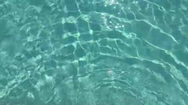 Açık mavi yüzme havuzu manzarası. Güneş yansımaları ve yumuşak dalgalar. Ferahlatıcı ve rahatlatıcı yaz sahnesi, sağlık, spa veya tatil teması için mükemmel.