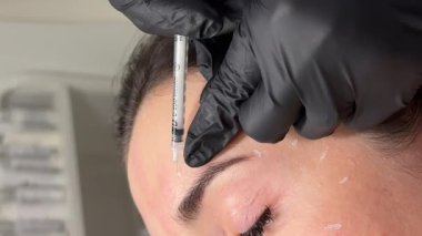 Güzellik kliniği. Eldiven giymiş güzellik uzmanları kadın derisine yüz yaşlanma enjeksiyonu yapıyor. Bir kadın güzellik yüz kozmetolojisi prosedürünü uygular. Botoks. Kolajen enjeksiyonları. 