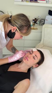 Güzellik kliniği. Eldiven giymiş güzellik uzmanları kadın derisine yüz yaşlanma enjeksiyonu yapıyor. Bir kadın güzellik yüz kozmetolojisi prosedürünü uygular. Botoks. Kolajen enjeksiyonları. 