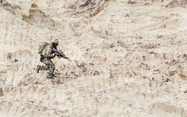 Soldier with carbine running alone through desert clipart
