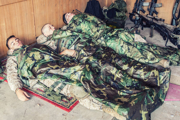 Tired soldiers sleeping on floor at temporary base