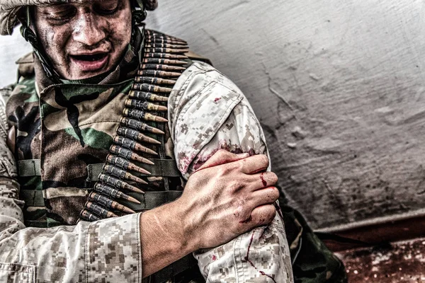 Поранений в плечі солдат намагається зупинити кровотечу — стокове фото
