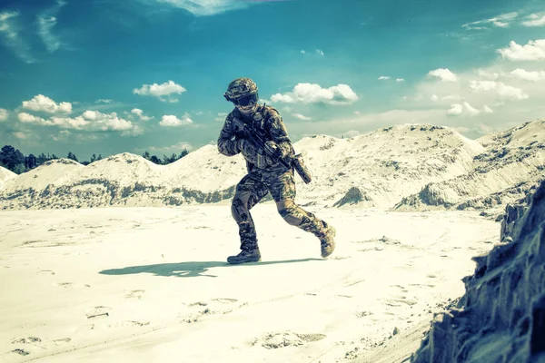 Man in military uniform playing airsoft in sands