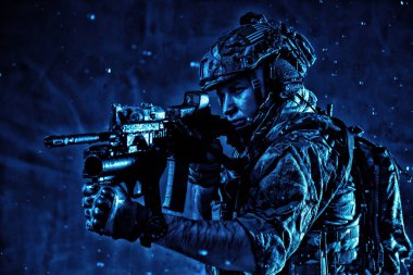 Gece yağmur altında servis tüfeği hedefleyen asker