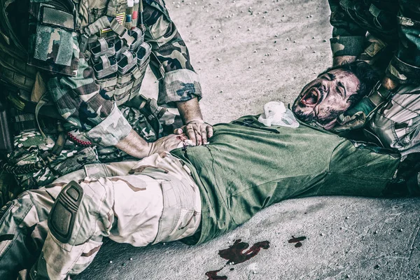 Soldier giving emergency care to wounded comrade — Stock Photo, Image