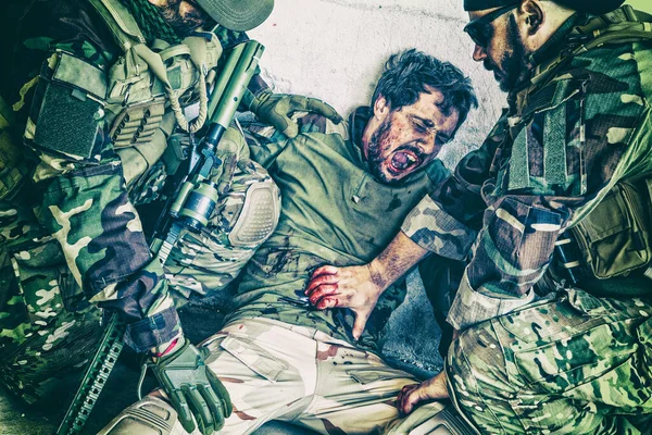 Soldiers helping wounded in stomach comrade — Stock Photo, Image