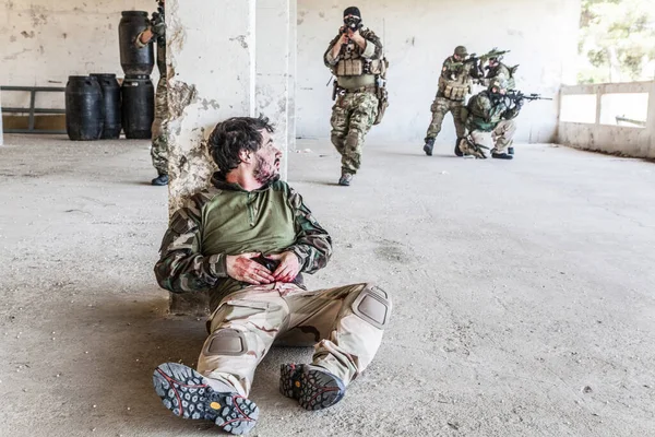 Herido en un soldado armado esperando ayuda —  Fotos de Stock