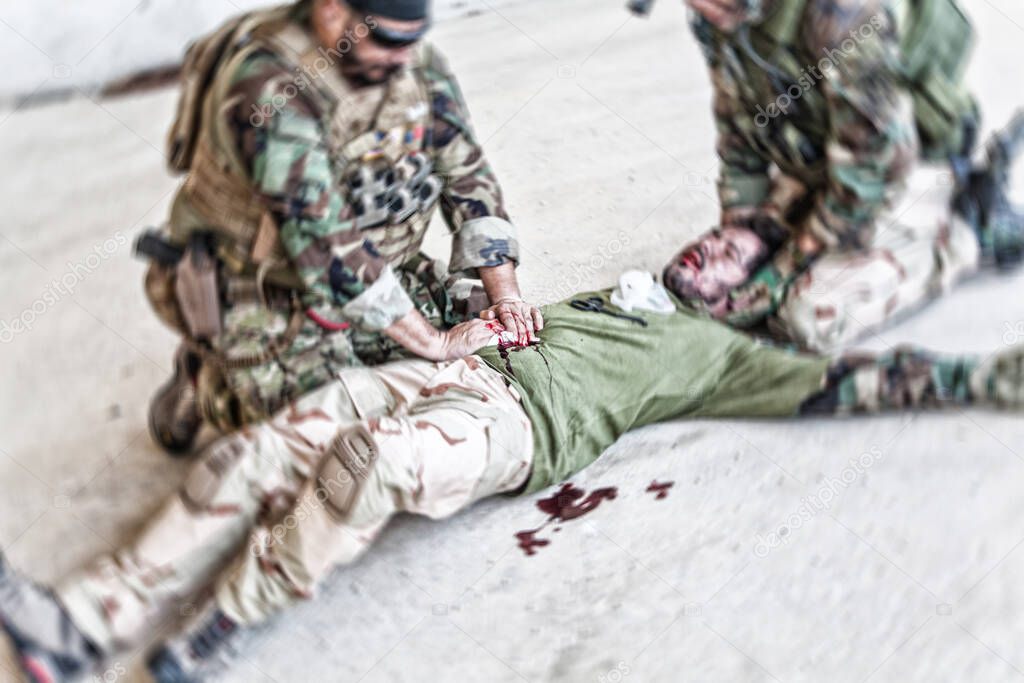 Soldier giving emergency care to wounded comrade