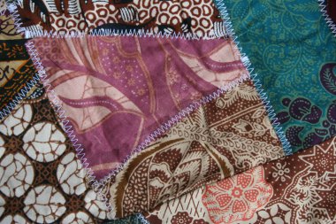 Batik material background, Indonesian material pieced together with white zigzag stiches in crazy quilt design in colorful blue green pink and brown colors