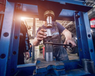 Araba tamir servis istasyonunda makinist basın yeni silentblock. Oto servisi. Arka plan