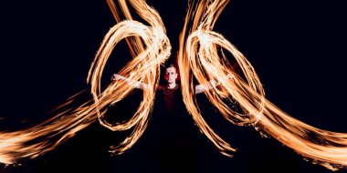 Gösteri yangın. Karanlıkta ateş performans gösteren genç adam.