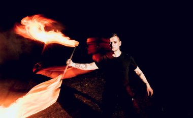 Gösteri yangın. Karanlıkta ateş performans gösteren genç adam.