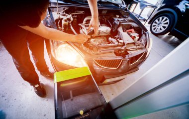 İşçi bir arabanın ışıklandırma sisteminin farlarını kontrol eder ve ayarlar. Otomatik onarım servisi.