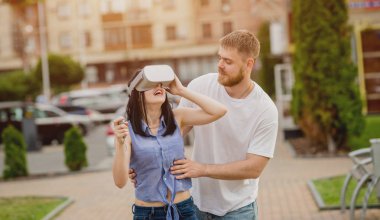 Genç çift sanal gerçeklik gözlükle sokakta bir oyun oynuyor. VR kulaklık.