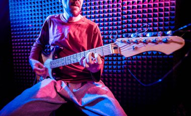 Genç adam gitar ses kayıt stüdyosu içinde oynamaya. Modern arka plan