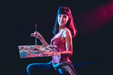 Stüdyoda iş yerinde genç sanatçı. Arka planda büyük tuval