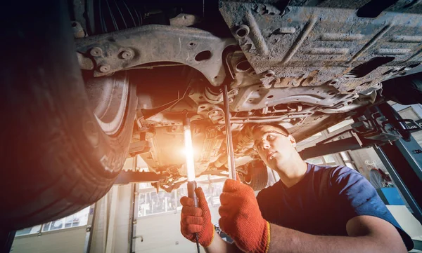 Kfz Mechaniker Bei Der Untersuchung Der Fahrwerksaufhängung Des Angehobenen Fahrzeugs — Stockfoto