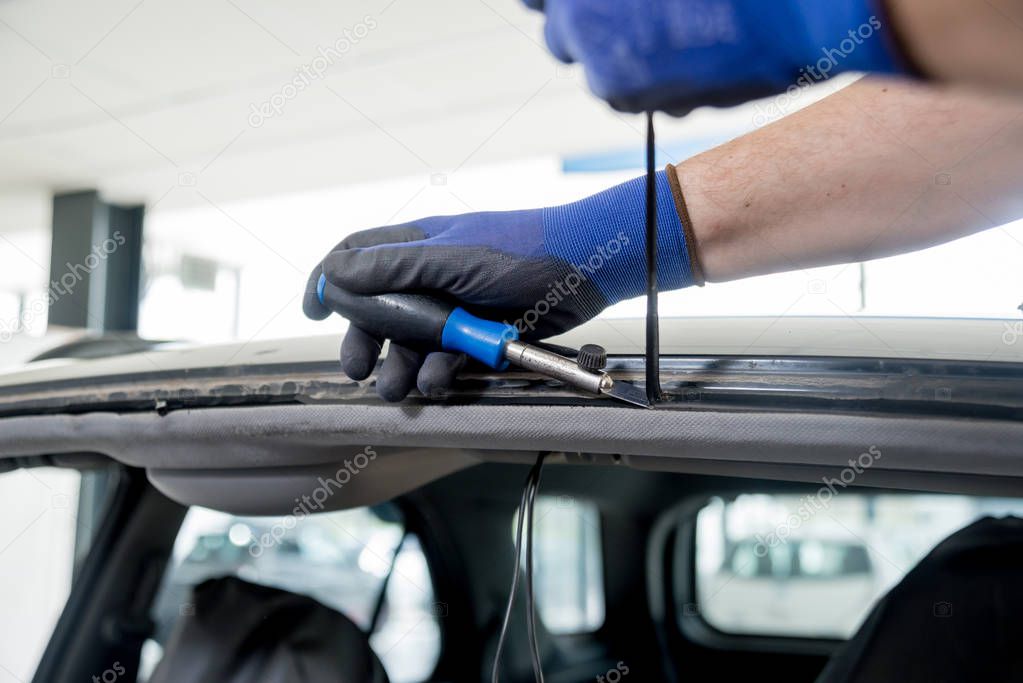 Automobile special worker remove old windscreen or windshield of a car in auto service station garage. Background