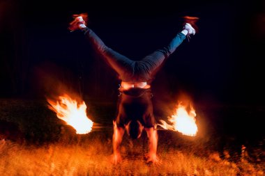 Gösteri yangın. Karanlıkta ateş performans gösteren genç adam.