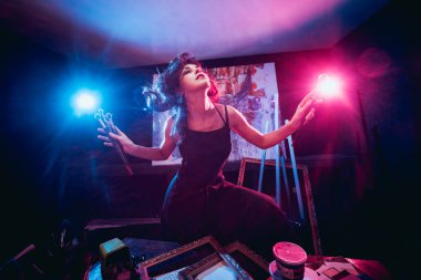 Stüdyoda iş yerinde genç sanatçı. Arka planda büyük tuval