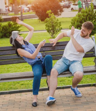 Genç çift sanal gerçeklik gözlükle sokakta bir oyun oynuyor. VR kulaklık.