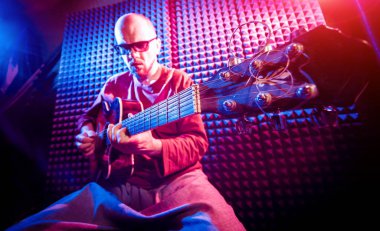 Akustik gitar ses kayıt Studio oynayan genç adam. Modern arka plan