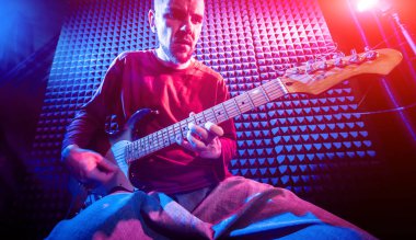 Genç adam gitar ses kayıt stüdyosu içinde oynamaya. Modern arka plan